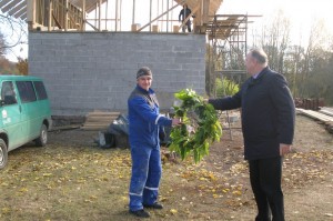 Pagėgių savivaldybės meras Virginijus  Komskis perduoda statybininkams stogo pabaigtuvių vainiką+.